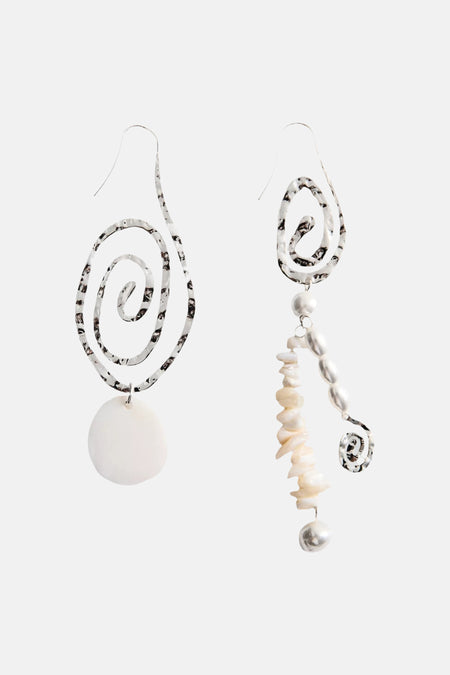 Boucle d'oreille multicolore de MANGO, spirale dorée avec perles et coquillages, portée par un mannequin aux cheveux mouillés et un haut blanc à paillettes.