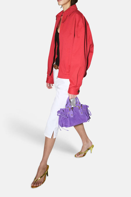 Pantalon blanc 5 poches de MANGO, longueur capri avec fentes, stylisé avec une veste rouge et un sac violet.