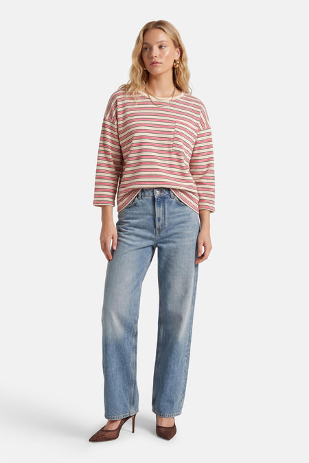 Roze T-shirt met lange mouwen van Terra di Siena, gestreept patroon en een borstzak, gecombineerd met blauwe jeans en bruine pumps.