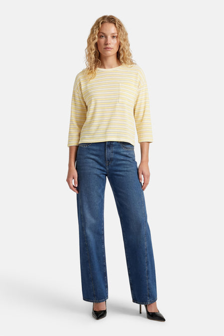 Geel gestreept T-shirt met lange mouwen van Terra di Siena, met borstzakje en gecombineerd met donkerblauwe jeans en zwarte pumps.
