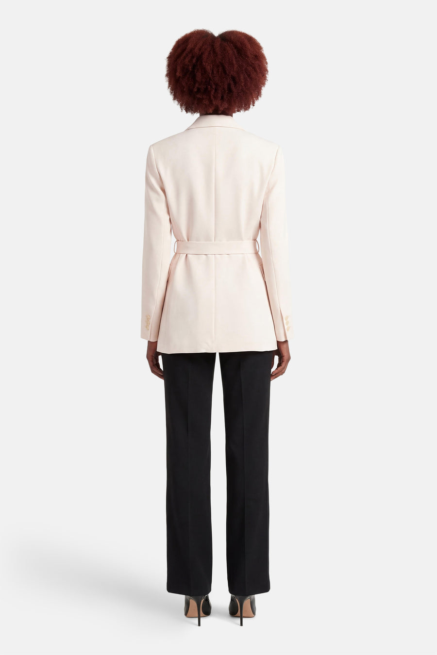Ecru blazer van MANGO, met ceintuur en gedragen met zwarte pantalon en hoge hakken.