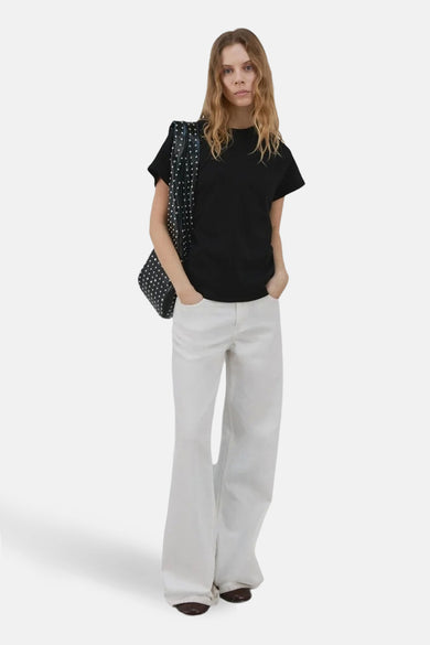 Haut noire de MANGO, à manches courtes et portée avec un pantalon blanc et un sac à pois.