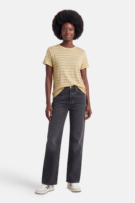 T-shirt jaune à rayures de MANGO, porté par un mannequin avec un jean foncé et des baskets.