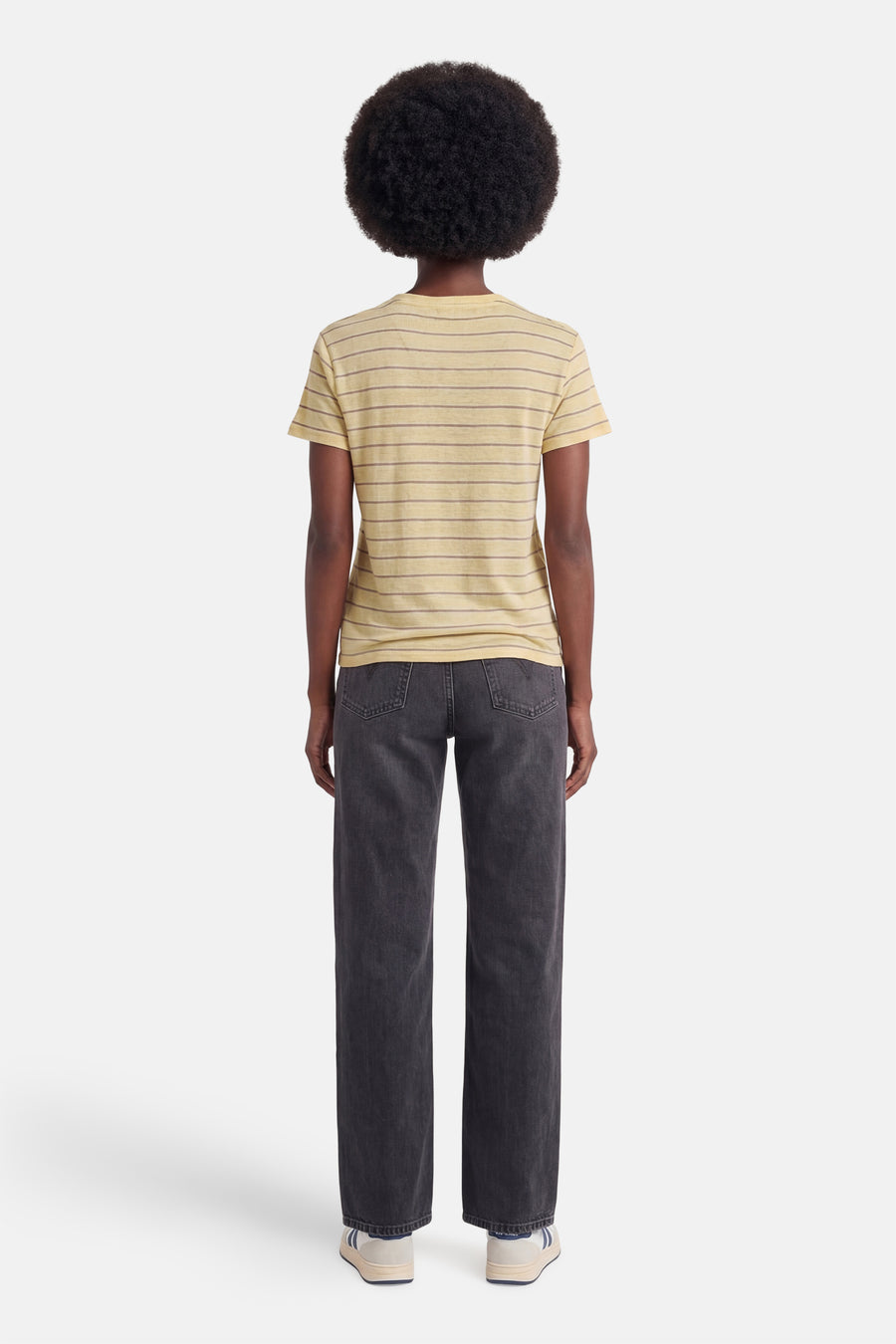 T-shirt jaune à rayures horizontales de MANGO, vu de dos, combiné avec un jean foncé et des baskets blanches.
