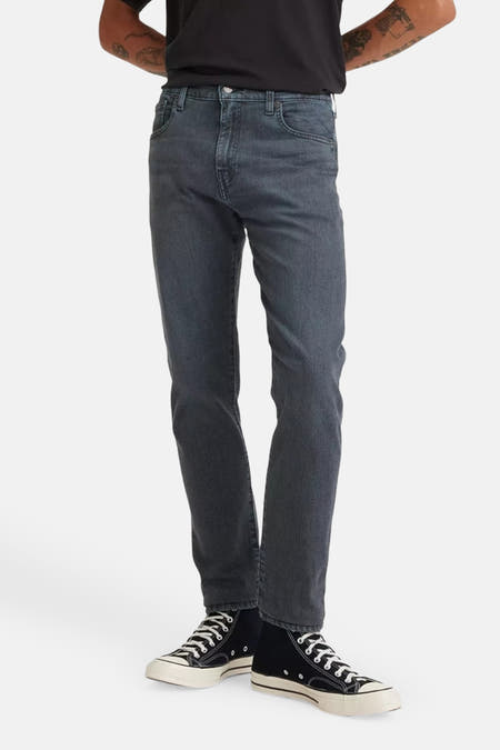 Jean tapered en denim noir de Levi's, associé à des baskets en toile noires.