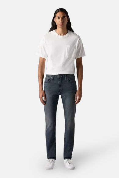 Tapered donkergrijze jeans van denim van Levi's®, gedragen met een wit T-shirt en witte sneakers.
