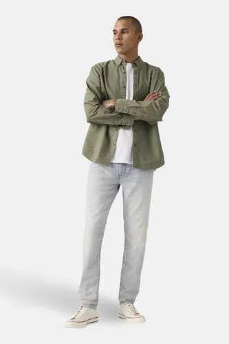 Taps toelopende jeans van lichtblauw denim van Levi's®, gecombineerd met een wit T-shirt en witte sneakers.