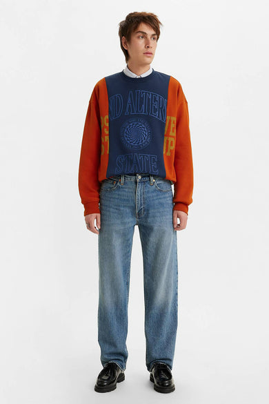 Rechte jeans van midblauw denim van Levi's, gedragen met een bedrukte trui en zwarte schoenen.
