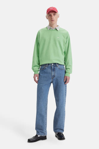 Jean bleu de denim de Levi's, porté avec un pull vert et des loafers noirs.