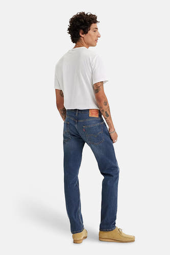 Blauwe jeans met taps toelopende pijpen van Levi's, gezien van achteren, gecombineerd met een wit T-shirt en suède schoenen.