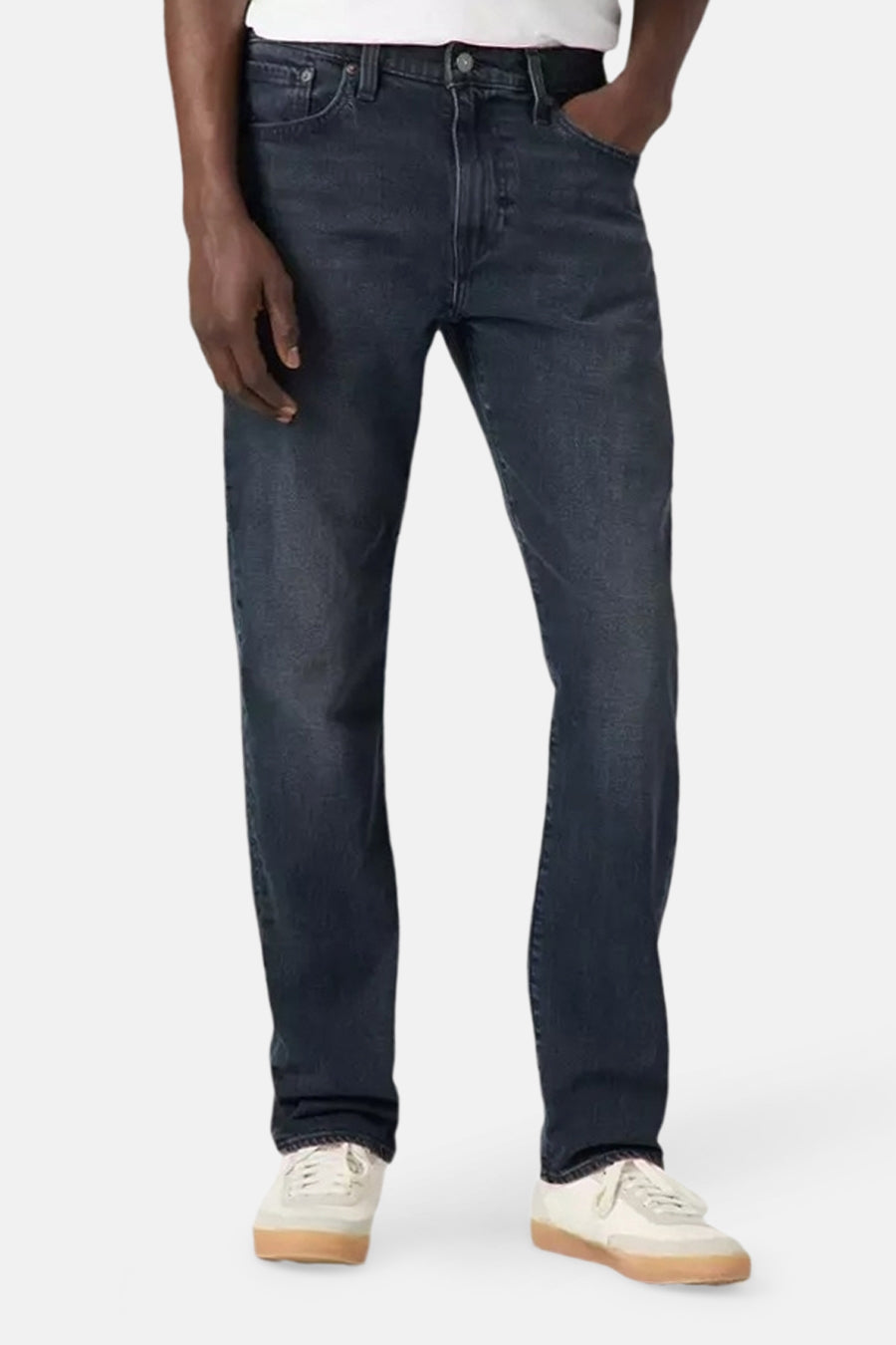 Een man in donkere jeans en witte sneakers.