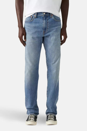 Lichtblauwe tapered jeans van Levi's, gedragen met een wit t-shirt en zwart-witte sneakers.
