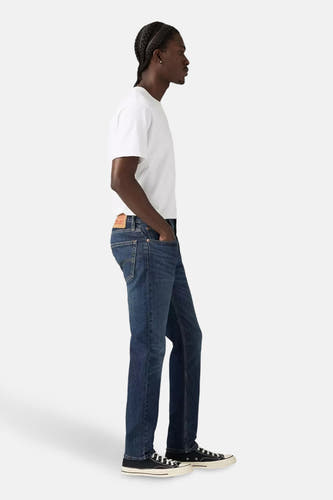 Jean tapered bleu marine en denim de Levi's, associé à un T-shirt blanc et des chaussures en toile noires.