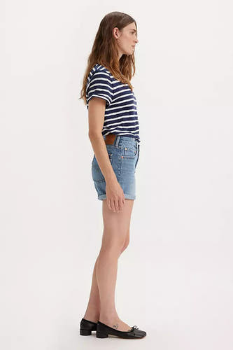 Short en denim Levi's, with rolled-up sleeves, combined with a striped top and black shoes, in profile view.