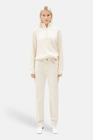 Jean mom blanc cassé d'ARMED ANGELS, porté avec un pull crème à fermeture éclair et des chaussures blanches.