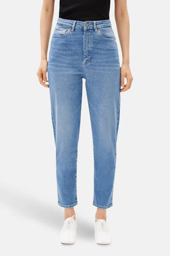 Jean mom bleu moyen d'ARMED ANGELS, avec une taille haute et des jambes droites, associé à des chaussures blanches.