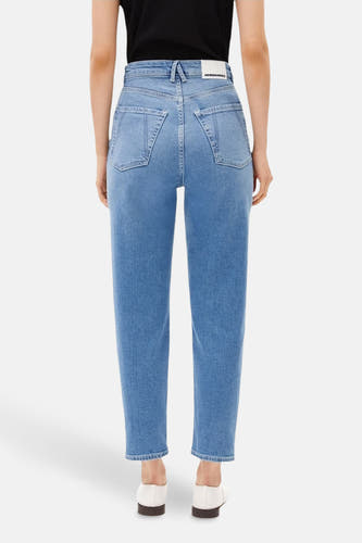 Jean mom bleu ARMED ANGELS avec une taille haute et des poches arrière, associé à des chaussures blanches.