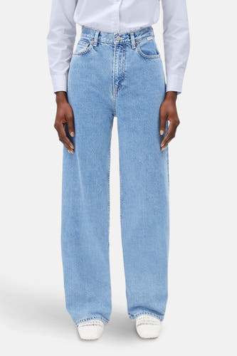 Jean bleu clair large d'ARMEDANGELS, porté avec un chemisier blanc et des espadrilles blanches.