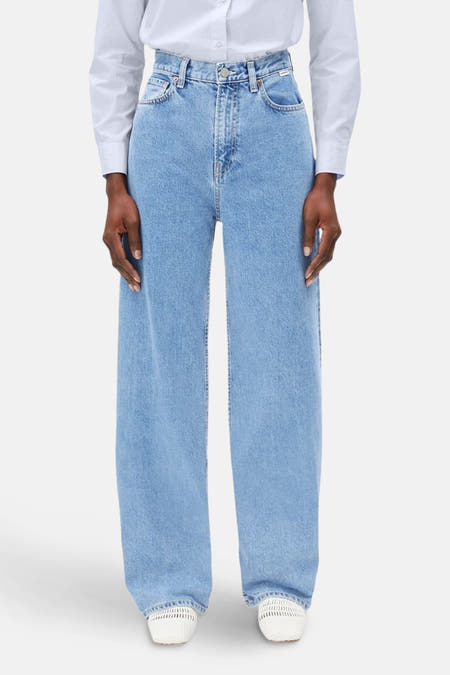 Jean bleu clair large d'ARMEDANGELS, porté avec un chemisier blanc et des espadrilles blanches.