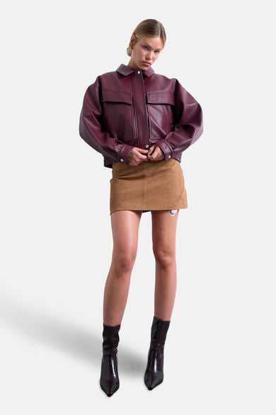 Manteau court de bordeaux de TOPSHOP, porté avec une jupe en cuir de mouton brun et des bottines brunes.