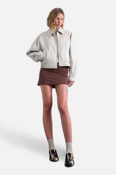 Mauve court manteau de TOPSHOP, avec une fermeture éclair argentée et porté avec une jupe brune.