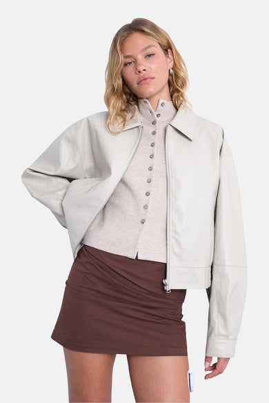 Mauve court manteau de TOPSHOP avec des manches longues, porté sur une chemise beige à boutons et une jupe brune.