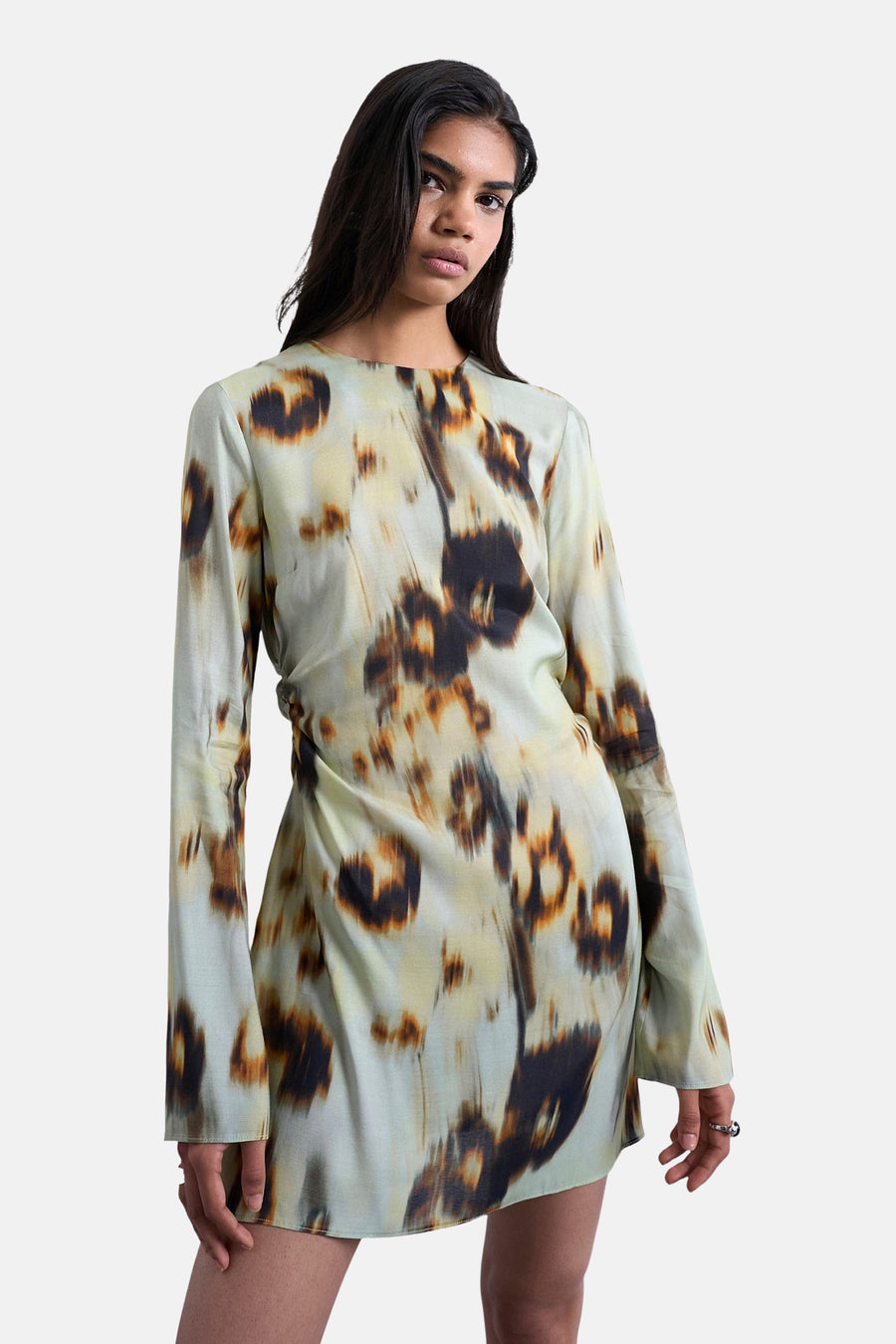 Model in groene jurk met lange mouwen.