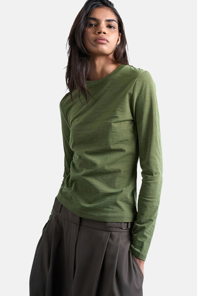 T-shirt vert avec manches longues de TOPSHOP, porté avec un pantalon marron à larges plis.