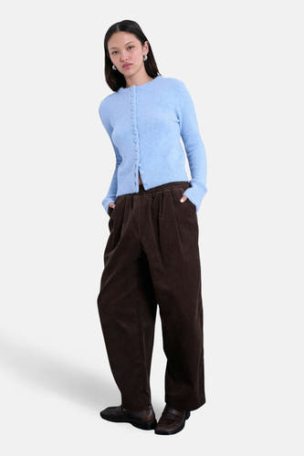 Veste bleue de TOPSHOP, avec des manches longues et une fermeture à boutons, portée avec un pantalon en corduroy marron.
