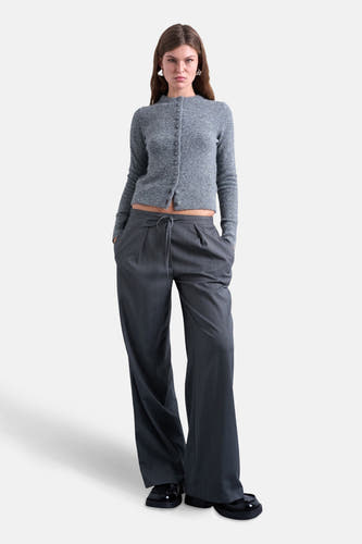 Cardigan gris de TOPSHOP, avec des manches longues et une fermeture à boutons, porté avec un pantalon gris et des chaussures noires.