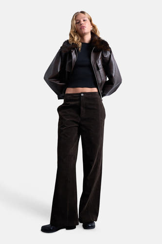T-shirt noir à manches courtes de TOPSHOP, porté avec une veste en cuir marron et un pantalon corduroy marron foncé.