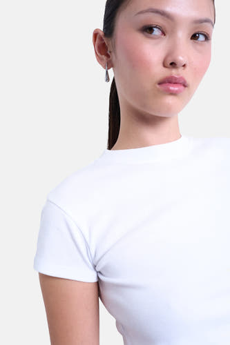 T-shirt blanc à manches courtes de TOPSHOP, porté par un modèle avec des boucles d'oreilles en argent.