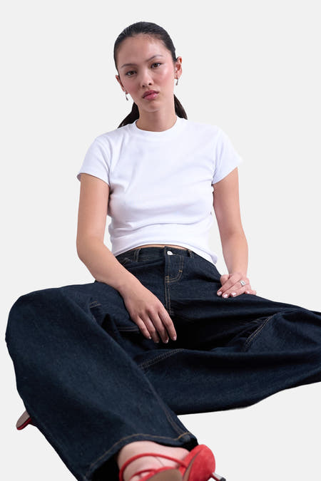 T-shirt blanc à manches courtes de TOPSHOP, porté avec des jeans foncés et des chaussures rouges.
