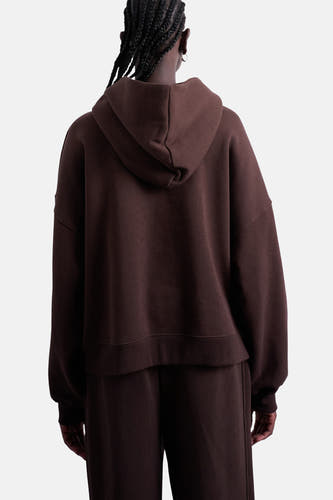 Pull marron avec capuche de TOPSHOP, vu de derrière, avec un short de jogging coordonné et des cheveux tressés.
