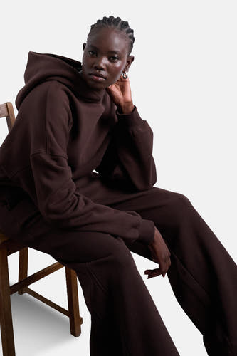Pull-over marron avec capuche de TOPSHOP, modèle assis avec des boucles d'oreilles en argent et un pantalon coordonné.