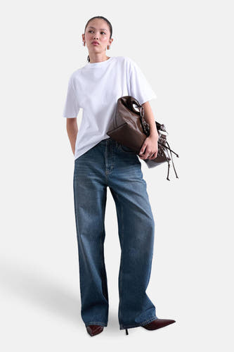 T-shirt blanc à manches courtes de TOPSHOP, porté avec des jeans larges et des baskets marrons.