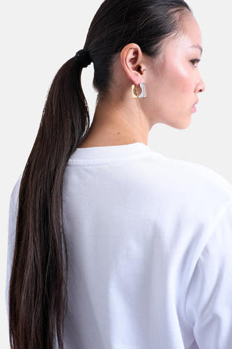 T-shirt blanc à manches courtes de TOPSHOP, avec une femme aux cheveux noirs portant un queue de cheval et des boucles d'oreilles carrées.