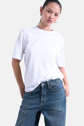 T-shirt blanc à manches courtes de TOPSHOP, porté avec des jeans et des boucles d'oreilles en or.
