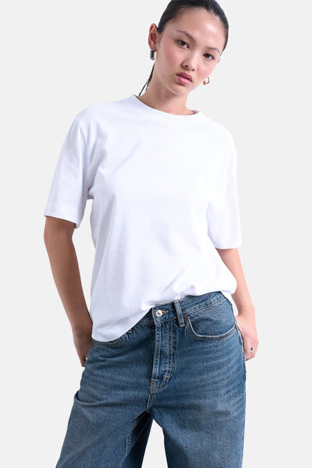 T-shirt blanc à manches courtes de TOPSHOP, porté avec des jeans et des boucles d'oreilles en or.