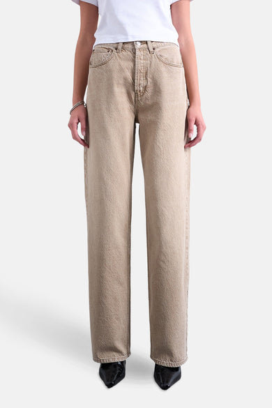Jean droit beige de TOPSHOP, porté avec un T-shirt blanc et des chaussures noires.