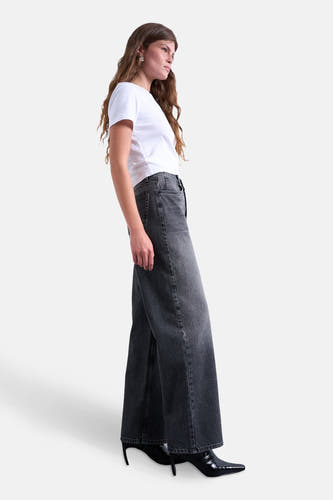 Jean droit noir de TOPSHOP, porté avec un T-shirt blanc et des bottes noires, en vue latérale.
