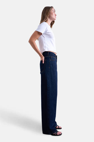 Jean bleu marine droit de TOPSHOP, avec un modèle en t-shirt blanc et sandales noires, en vue latérale.