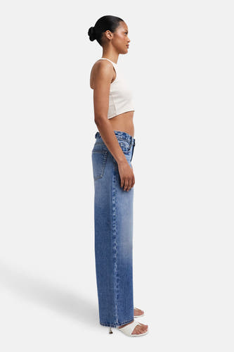 Jean droit bleu marine en denim de TOPSHOP, vu de côté, associé à une chemise blanche et des baskets blanches.