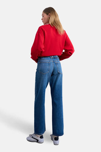Jean droit en denim bleu moyen de TOPSHOP, avec une taille haute et stylisé avec un pull rouge.