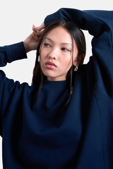 T-shirt bleu avec col rond de TOPSHOP, à longues manches et porté avec des boucles d'oreilles en argent.