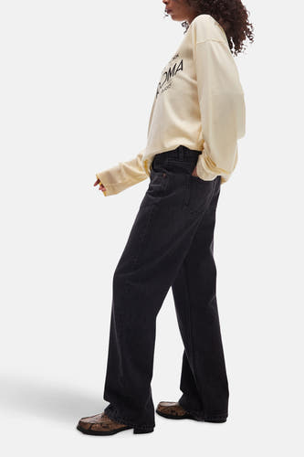 Zwarte wijde jeans van TOPSHOP, gecombineerd met een crèmekleurige sweater en slangenleren loafers.