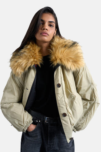 Groene korte jas van TOPSHOP, met een grote bontkraag en knoopsluiting, gedragen met een zwarte top en jeans.
