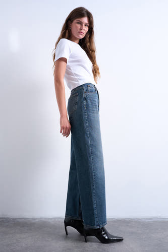 Jean droit en denim bleu de Topshop, avec une taille haute et des talons noirs.