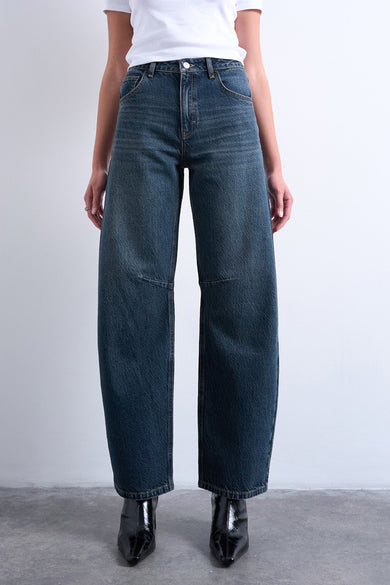 Jean spécial ajusté en denim bleu-noir de TOPSHOP, avec des jambes larges, associé à un T-shirt blanc et des bottines noires.