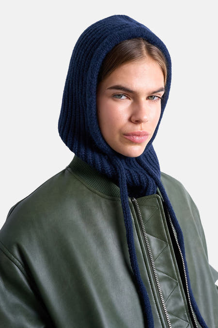 Chapeau bleu de TOPSHOP, porté avec une veste en cuir olive et un pantalon gris.